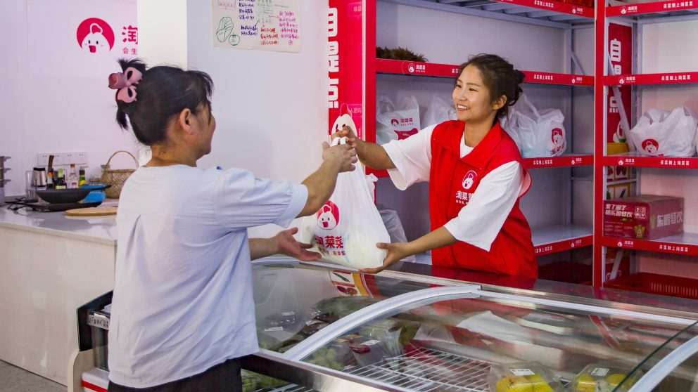 Cliente pega pedido de supermercado em uma loja de conveniência afiliada de Taocaicai
