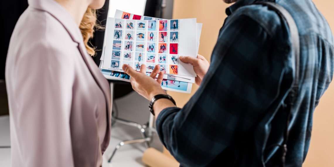 cropped shot of photographer and model looking at photos in studio